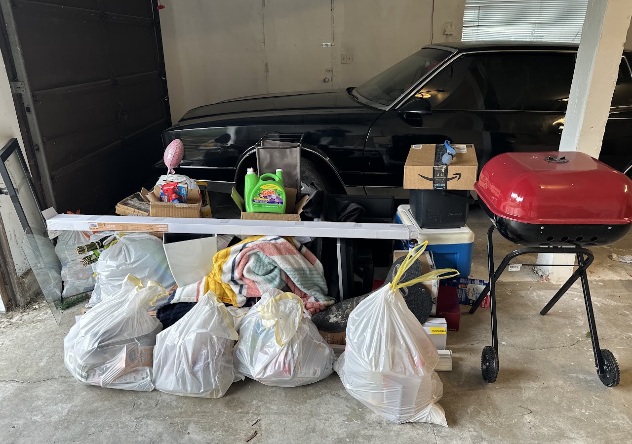 Bags, boxes and a grill piled in a garage, ready for a cleanout